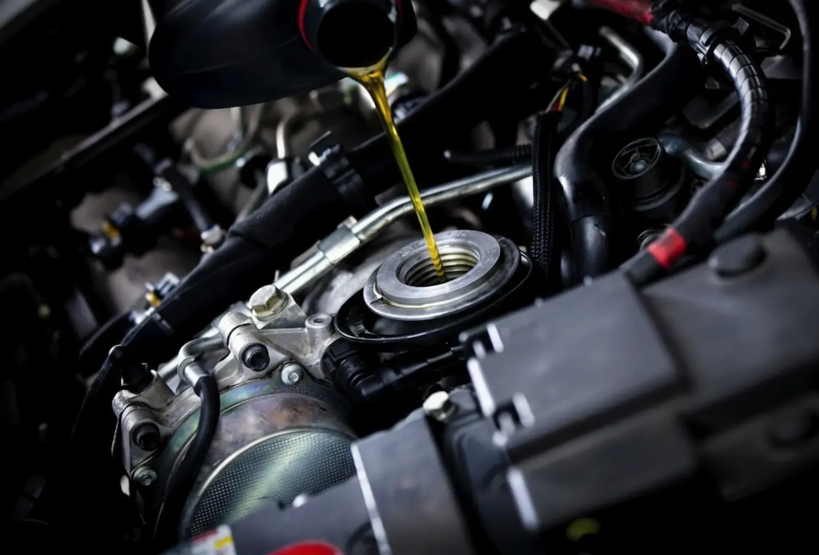 Mechanic Services: Detailed shot of motor oil being added to a vehicle's oil port during a scheduled maintenance service.