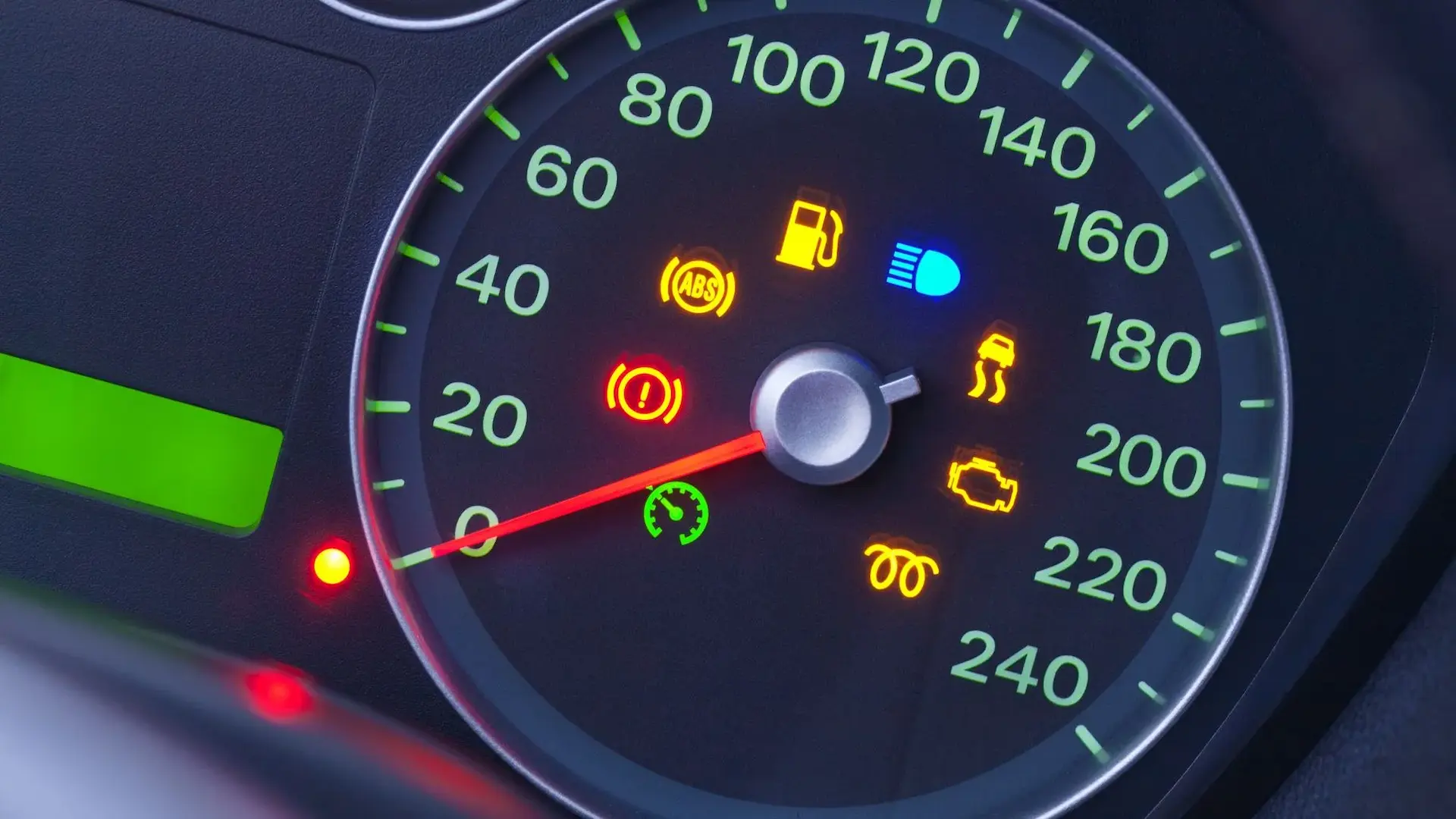 Engine light: A modern speedometer illuminated at night showing active icons for low fuel, high beams, check engine, and glow plugs.