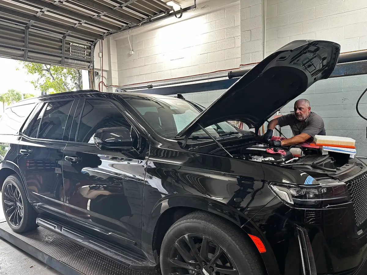 Mechanic performing preventative maintenance inspection on black luxury SUV
