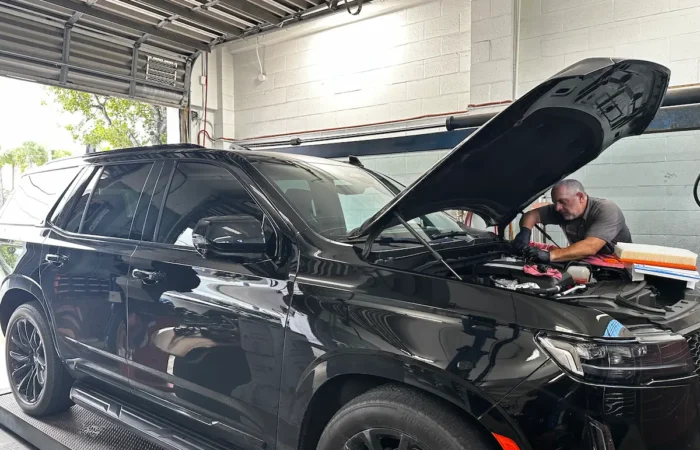 A mechanic performing a luxury SUV engine inspection at an independent auto repair shop in Fort Lauderdale.