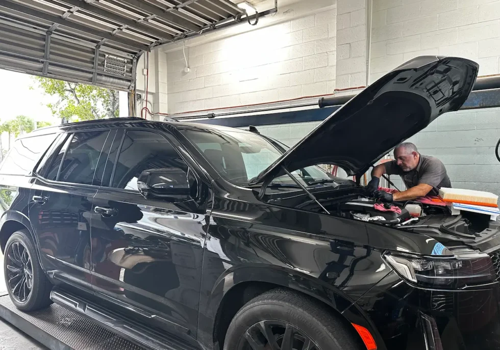 A mechanic performing a luxury SUV engine inspection at an independent auto repair shop in Fort Lauderdale.