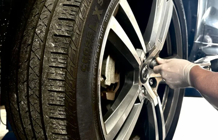 Mechanic performing tire rotation and wheel inspection on Mercedes vehicle