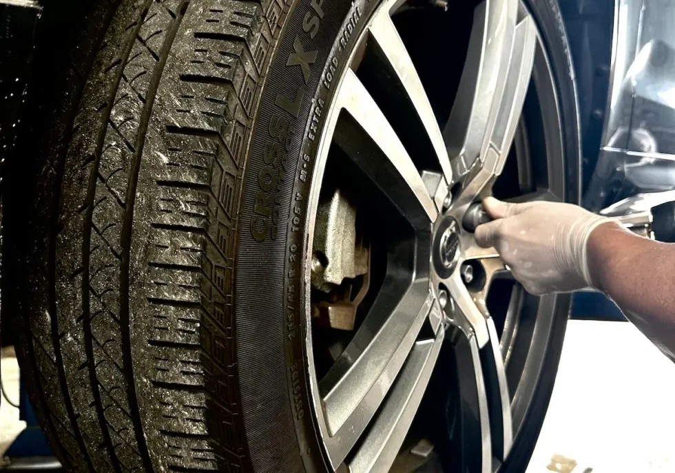 Mechanic performing tire rotation and wheel inspection on Mercedes vehicle