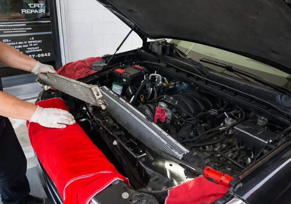 Mechanic removing radiator from car engine during vehicle repair service in professional auto shop