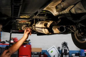 Mechanic performing catalytic converter repair on a vehicle exhaust system in an auto repair shop