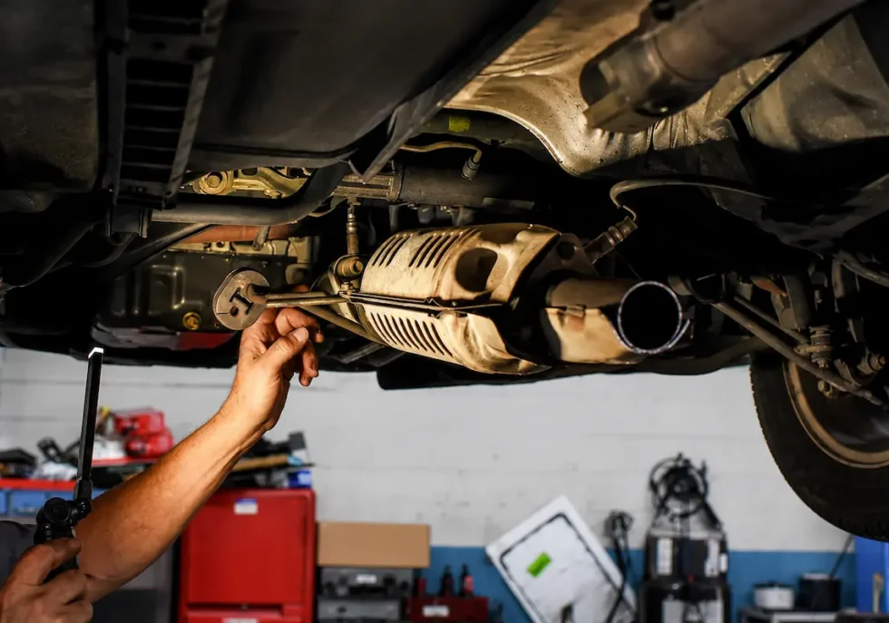 Mechanic performing catalytic converter repair on a vehicle exhaust system in an auto repair shop