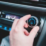 Driver adjusting the car air conditioning controls, serviced by Southport Auto Repair in Fort Lauderdale
