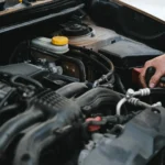 Technician servicing a car battery in the engine bay at Southport Auto Repair in Fort Lauderdale